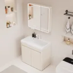 Modern bathroom setup featuring a beige vanity cabinet and illuminated mirror cabinet. Includes shelves with toiletries and wall-mounted towel rack.