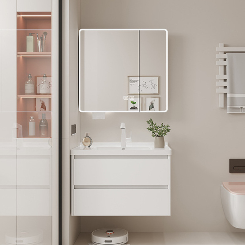 Contemporary bathroom setup featuring a sleek white vanity with drawers, topped by a lit mirror cabinet and minimalist decor.